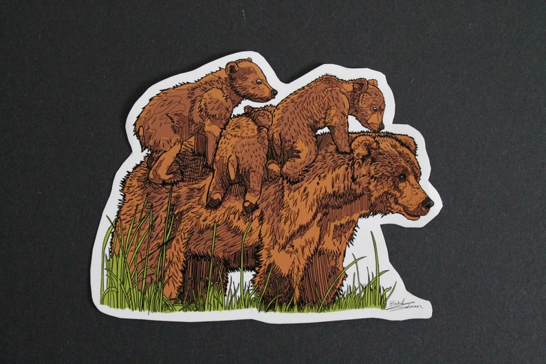 May include: A sticker featuring a brown bear with three cubs riding on its back. The illustration has a hand-drawn style with detailed linework and a touch of green grass at the bottom. The sticker is on a black background.