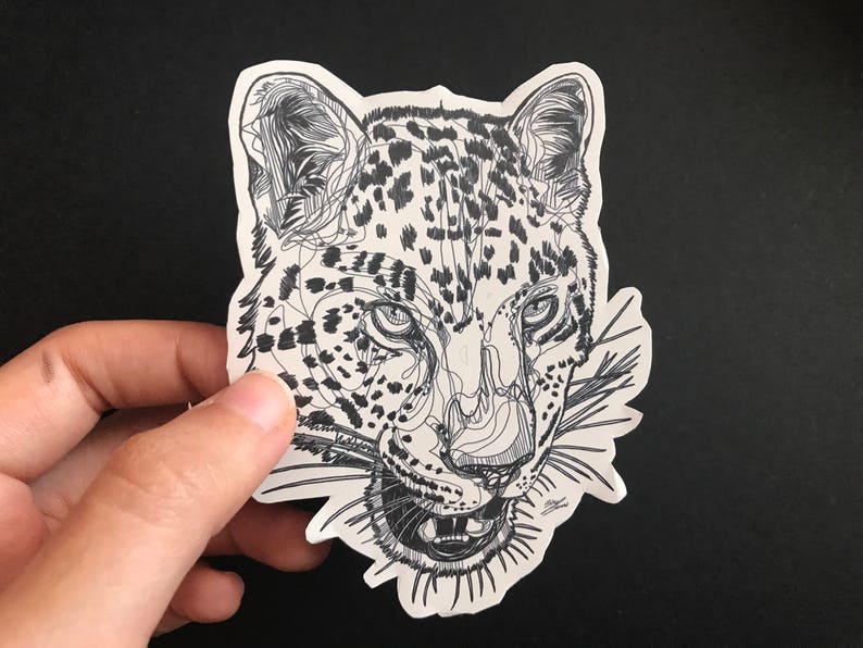 May include: A black and white line drawing of a leopard's face with a detailed depiction of its fur and whiskers.