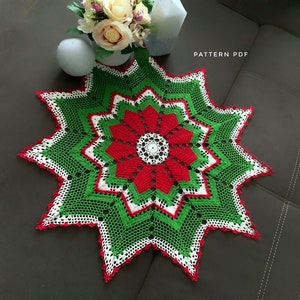 May include: A green, white, and red crochet doily with a starburst design. The doily has a red flower in the center with a white center. The text "PATTERN PDF" is visible in the upper right corner of the image.