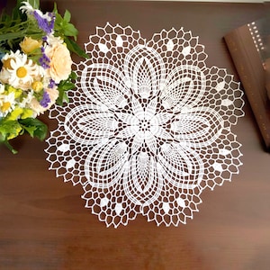 May include: White crocheted doily with a delicate floral design. The doily is circular and has a lace pattern.