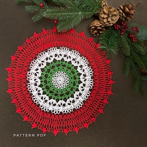May include: A handmade, crocheted doily in a festive color scheme. The circular design features concentric rings of red, white, and green, with a detailed, openwork pattern. The text "PATTERN PDF" is visible at the bottom.