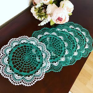 Op de afbeelding: Set van vijf groene en witte gehaakte placemats met een gegolfde rand.