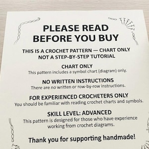 May include: A printed paper with the text "PLEASE READ BEFORE YOU BUY" and other crochet pattern details. A ball of yarn and a crochet hook are in the background. The pattern is for experienced crocheters.