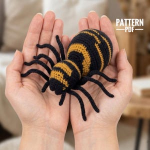 May include: A crochet spider toy featuring a black and mustard yellow striped pattern on its rounded body and eight thin black legs. The text PATTERN PDF is visible in the upper right corner of the image, indicating this is a digital file.