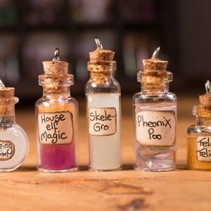 May include: Five small glass bottles with cork stoppers and handwritten labels. The labels read "House Elf Magic", "Skele-Gro", "Phoenix Poo", "Ageing Potion", and "Felix Felicis".