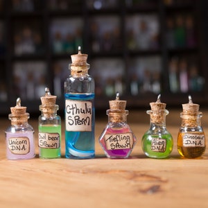 May include: Seven small glass bottles with cork stoppers and labels. The labels have handwritten text, including "Unicorn DNA", "Owl Bear Spawn", "Cthulhu Sperm", "Tiefling Spawn", "Alien DNA", and "Dinosaur DNA".