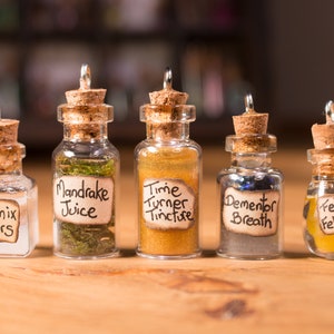 May include: Five small glass bottles with cork stoppers and labels. The labels read "Phoenix Tears", "Mandrake Juice", "Time Turner Tincture", "Dementor Breath", and "Felix Felicis".