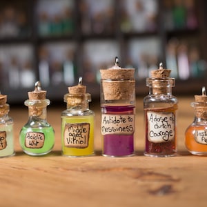 May include: Seven small glass bottles with cork stoppers and handwritten labels. The labels include phrases like "Can do Spirit", "Acidic Wit", "Middle aged Vitriol", "Antidote to Messiness", "Adose of Dutch Courage", and "Instant Pep".