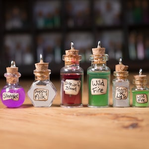 May include: Seven small glass bottles with cork stoppers and handwritten labels. The labels read "Strangler", "Poppy Milk", "Direwolf Blood", "Wild Fire", "Tears of Lys", and "Wild Fire".