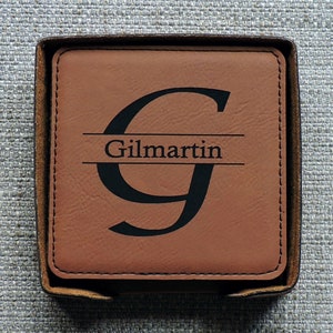 May include: A brown leather coaster with a black initial "G" and the name "Gilmartin" engraved on it.