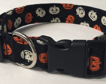 May include: Black dog collar with a Halloween pumpkin pattern. The collar has a black plastic buckle and a silver metal D-ring.