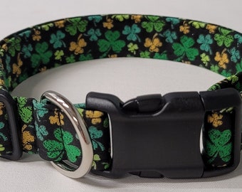 Könnte beinhalten: Ein schwarzes Hundehalsband mit einem grünen Kleeblatt-Muster. Das Halsband hat eine schwarze Kunststoffschnalle und einen silbernen D-Ring.