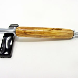 May include: A wooden pen with a silver metal tip and end cap. The pen is made of olive wood with a natural grain pattern.
