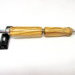 May include: A wooden pen with a silver metal tip and a brown and tan wood grain pattern.