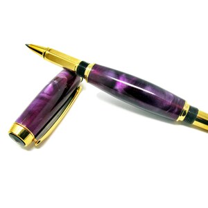 Op de afbeelding: Een paarse en gouden pen met een marmerpatroon. De pen is gesloten en ligt op een wit oppervlak.