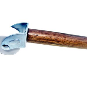 May include: A white roller with a metal frame and a wooden handle. The roller is used for applying wallpaper or other materials.