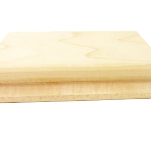 Op de afbeelding: Een rechthoekig houten blok met een glad, lichtbruin oppervlak. Het blok heeft afgeronde randen en een licht verhoogde lip aan de boven- en onderkant.