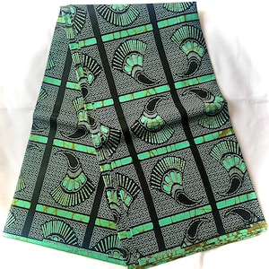 Könnte beinhalten: Ein gefaltetes Stück Stoff in Grün und Schwarz mit einem sich wiederholenden Muster aus stilisierten grünen Fächer auf schwarzem Hintergrund. Der Stoff hat den Text "VERITABLE UNICO HTG - A/A PRINTS" auf der Unterkante aufgedruckt.