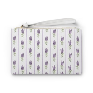 May include: A white zippered pouch with a lavender floral pattern and a white strap. The pouch has a repeating pattern of purple lavender flowers on a white background with thin purple stripes.