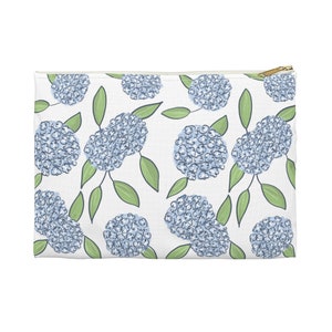 May include: A white zippered pouch with a repeating pattern of blue hydrangea flowers and green leaves.