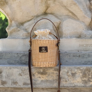 Natürlicher Weideneimerkorb mit langem Schultergurt aus Leder, einzigartige runde Tragegriff-Crossbody-Tasche aus Stroh, handgewebter Luxus-Tote für den Urlaub