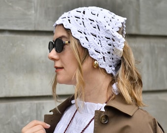 May include: A white, open-weave crochet head covering. The head covering is worn by a person wearing sunglasses, a white shirt, and a brown jacket. The head covering is made of a soft, breathable material.