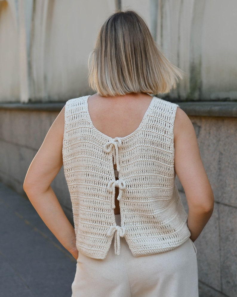 Pu&ograve; includere: Top all'uncinetto senza maniche color crema, con scollatura rotonda e schiena scoperta. La schiena &egrave; assicurata da delicati fiocchi. Il top &egrave; realizzato con un filato strutturato e ha una vestibilit&agrave; rilassata, adatta al clima caldo.
