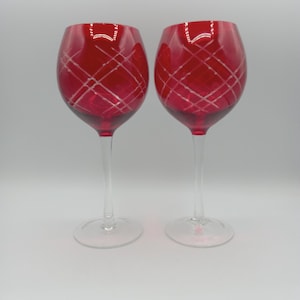 May include: Two red wine glasses with a criss-cross etched design.