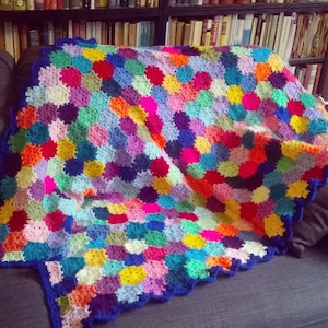 May include: A colourful crocheted blanket with a scalloped edge and a variety of bright colours, including pink, blue, green, yellow, and red.
