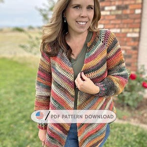 May include: A colorful, open-front crochet cardigan with a striped pattern in shades of red, orange, yellow, green, and brown. The text "PDF PATTERN DOWNLOAD" is visible on the bottom left. The cardigan is worn over a green top and blue jeans.