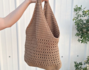 May include: A brown crocheted tote bag with a wide, open top and two long handles. The bag is made with a simple stitch pattern and has a slightly textured surface.
