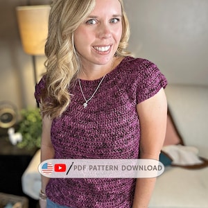 May include: A short-sleeved, burgundy crochet top. The top has a round neckline and is worn with blue jeans. The image includes the text "PDF PATTERN DOWNLOAD" and the website "hookedonhomemadehappiness.com".