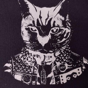 May include: Black and white illustration of a cat wearing a studded leather jacket. The cat has a serious expression and is looking directly at the viewer.