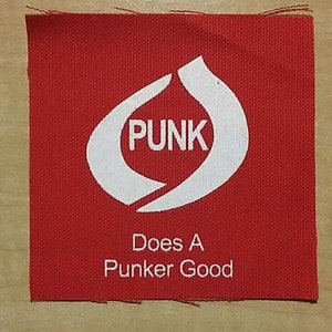 Op de afbeelding: Rode stoffen patch met een witte cirkel met het woord "PUNK" en de tekst "Does A Punker Good".