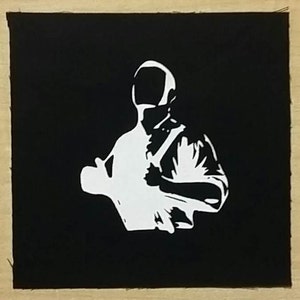 May include: A black and white silhouette of a person wearing a helmet, with a dark background.