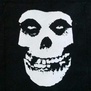 Può includere: Immagine in bianco e nero di uno scheletro con un ampio sorriso e grandi orbite oculari vuote. Lo scheletro è delineato in bianco e ha uno sfondo nero.
