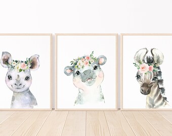 May include: Three watercolor animal prints featuring a rhino, a hippopotamus, and a zebra. Each animal is wearing a floral crown with pink and white flowers. The background is white.