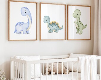 May include: Three framed watercolor dinosaur prints in a nursery setting. The dinosaurs are in shades of blue and green, with a white background. The frames are light brown. A white crib with a teddy bear and pillows is in the foreground.