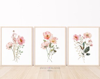May include: Set of three watercolor floral prints featuring pink and green flowers on a white background. The prints are framed in a light wood frame.
