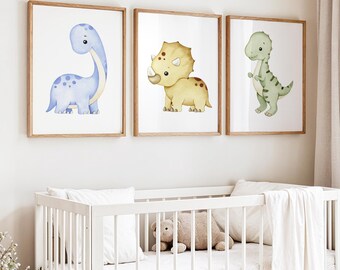 May include: Three framed watercolor dinosaur prints in a nursery setting. The dinosaurs are a blue Brontosaurus, a yellow Triceratops, and a green Tyrannosaurus Rex. The frames are light brown, and the nursery has a white crib with a teddy bear.