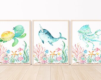May include: Three watercolor paintings of sea creatures. The first painting features a green sea turtle swimming in a coral reef. The second painting features a blue narwhal swimming in a coral reef. The third painting features a blue jellyfish swimming in a coral reef.