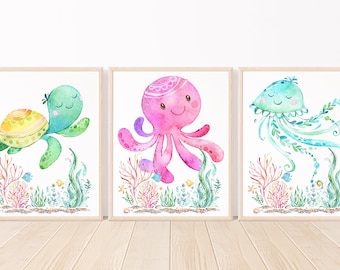 May include: Three watercolor illustrations of sea creatures. A green sea turtle with a yellow shell, a pink octopus with a white crown, and a blue jellyfish with green tentacles.