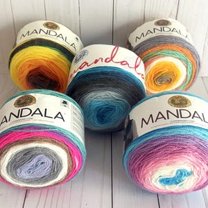 May include: Five skeins of Mandala yarn in different color combinations. The yarn is a gradient style with multiple colors in each skein. The colors include pink, purple, blue, teal, gray, white, yellow, orange, and brown.