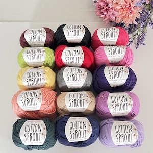 May include: A collection of 15 balls of yarn in various colors, including pink, purple, green, blue, and red. Each ball has a white label with the text "Cotton Sprout" and "100% Cotton".
