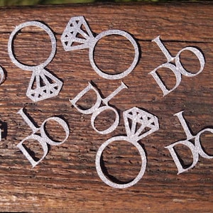 May include: Silver glitter confetti with the words "I Do" and images of rings with diamonds.
