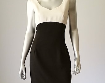 May include: A sleeveless dress with a white top and a black bottom. The dress has a sweetheart neckline and a fitted silhouette.