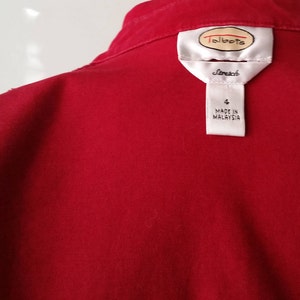 May include: A close-up of a red garment with a white label. The label features the brand name "Talbots" and the word "Stretch". Below the brand name, the label indicates size "4" and "MADE IN MALAYSIA".