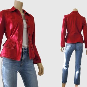 May include: A vibrant red jacket with a button-up design, two front pockets, and white stitching. The jacket has a tailored fit and is paired with blue jeans. The jacket is displayed on a mannequin.