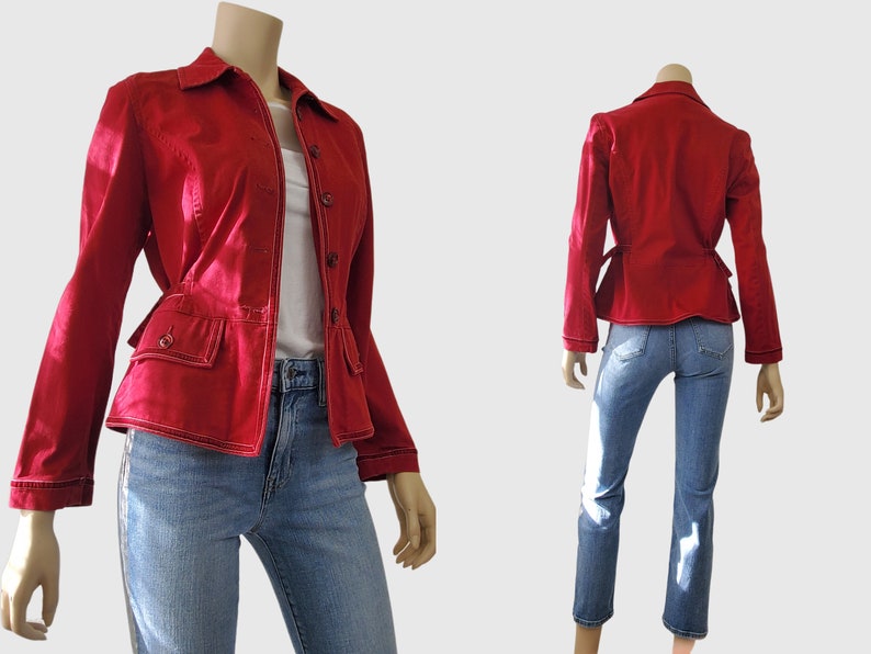 May include: A vibrant red jacket with a button-up design, two front pockets, and white stitching. The jacket has a tailored fit and is paired with blue jeans. The jacket is displayed on a mannequin.