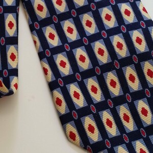 May include: A navy blue tie with a geometric pattern featuring red, white, and blue squares and diamonds.